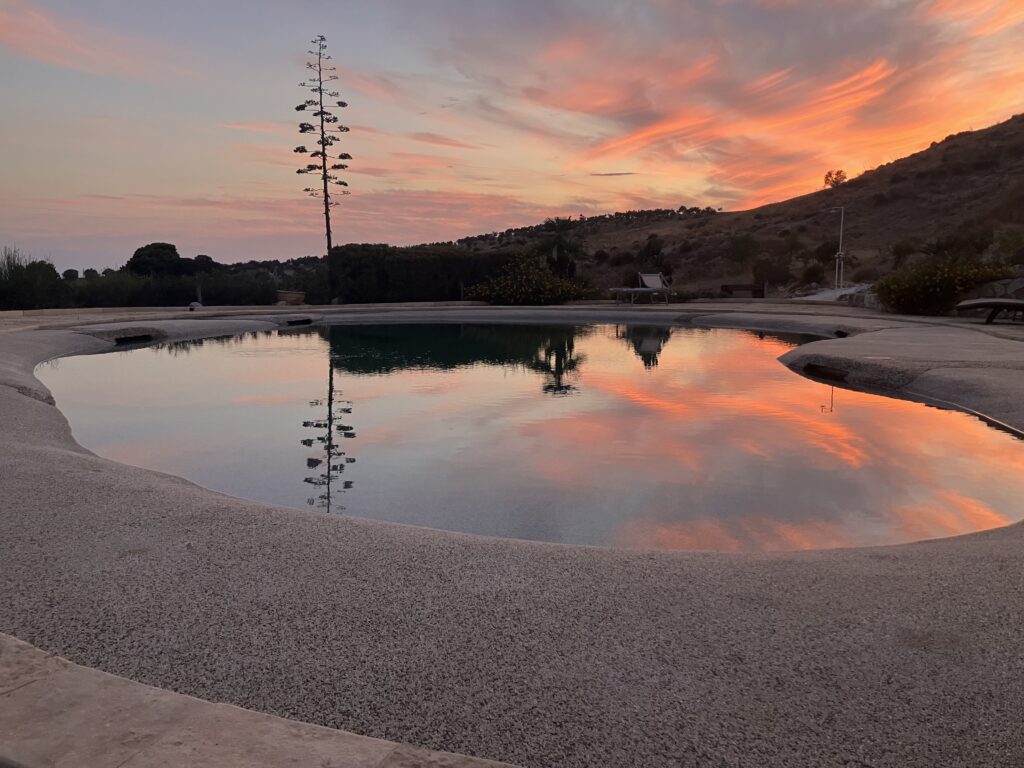Tramonto riflesso in piscina nel paesaggio collinare di un Agriturismo in Agrigento